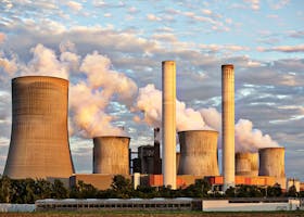 View of a power plant with smoke emissions under a cloudy sky, depicting industrial energy production.